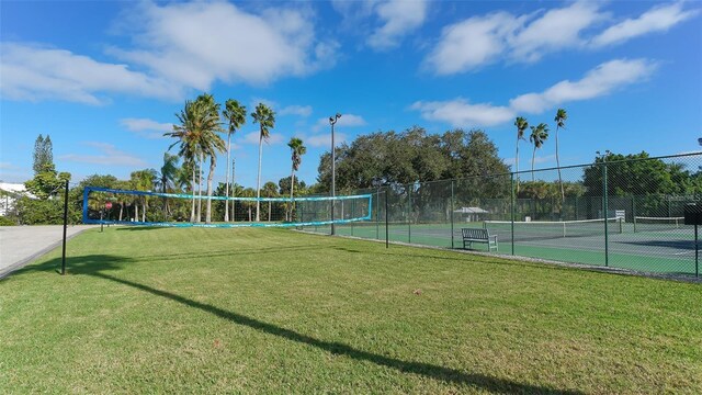 view of tennis court with volleyball court and a yard