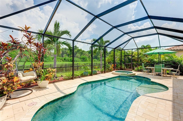 view of swimming pool with glass enclosure, an in ground hot tub, and a patio area