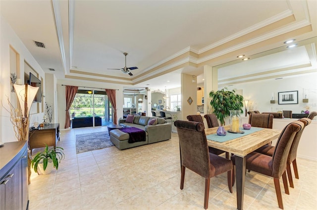 dining area featuring ceiling fan, ornamental molding, light tile patterned flooring, and a tray ceiling