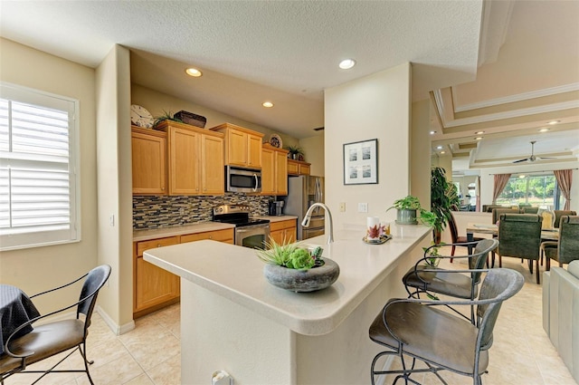 kitchen featuring stainless steel appliances, kitchen peninsula, ceiling fan, decorative backsplash, and light tile patterned flooring