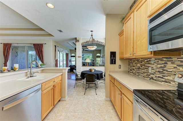 kitchen featuring stainless steel appliances, sink, light brown cabinets, tasteful backsplash, and hanging light fixtures