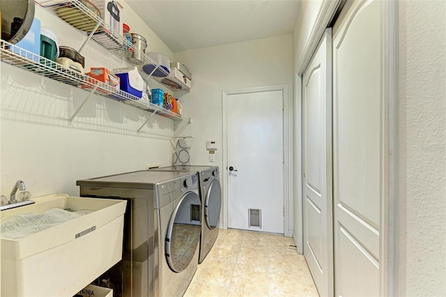 clothes washing area featuring sink, washing machine and clothes dryer, and light tile patterned floors