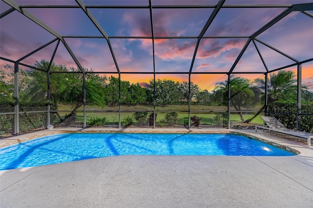 pool at dusk featuring a lanai and a patio