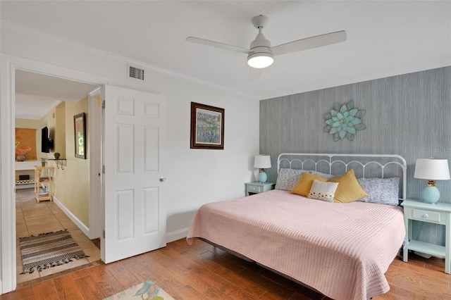 bedroom with hardwood / wood-style floors, crown molding, and ceiling fan