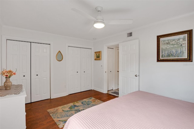 bedroom featuring multiple closets, ornamental molding, hardwood / wood-style floors, and ceiling fan