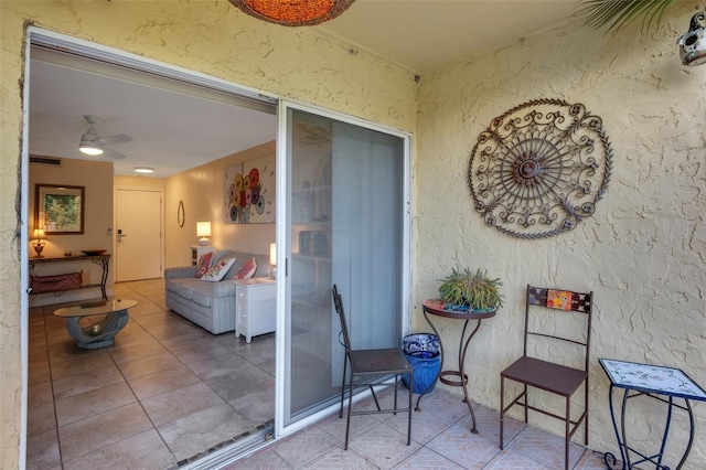 view of exterior entry featuring ceiling fan and a patio area