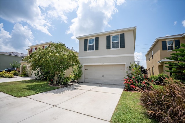 traditional-style house with a front lawn, driveway, an attached garage, and stucco siding