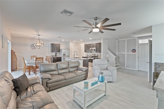 living room with ceiling fan with notable chandelier, stairs, visible vents, and recessed lighting