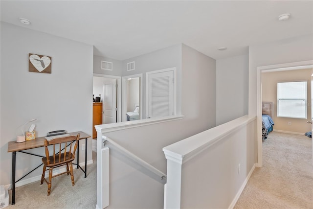 corridor featuring baseboards, light carpet, visible vents, and an upstairs landing