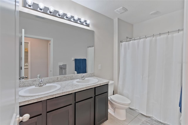 bathroom with double vanity, a sink, toilet, and tile patterned floors