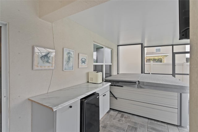 kitchen with light stone countertops, white cabinetry, and refrigerator