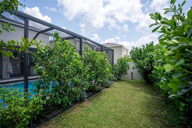 view of yard with a lanai, fence, and an outdoor pool