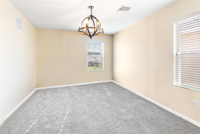 carpeted empty room with baseboards, visible vents, and a notable chandelier