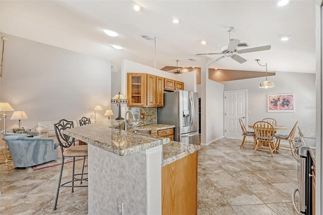 kitchen featuring a kitchen bar, kitchen peninsula, tasteful backsplash, stainless steel appliances, and vaulted ceiling