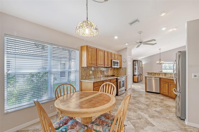 tiled dining room with ceiling fan with notable chandelier and vaulted ceiling