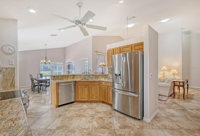 kitchen featuring sink, light stone counters, lofted ceiling, ceiling fan with notable chandelier, and appliances with stainless steel finishes