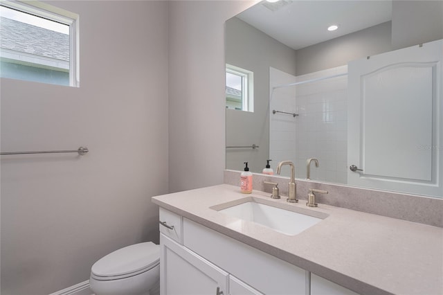 bathroom with tiled shower, vanity, and toilet