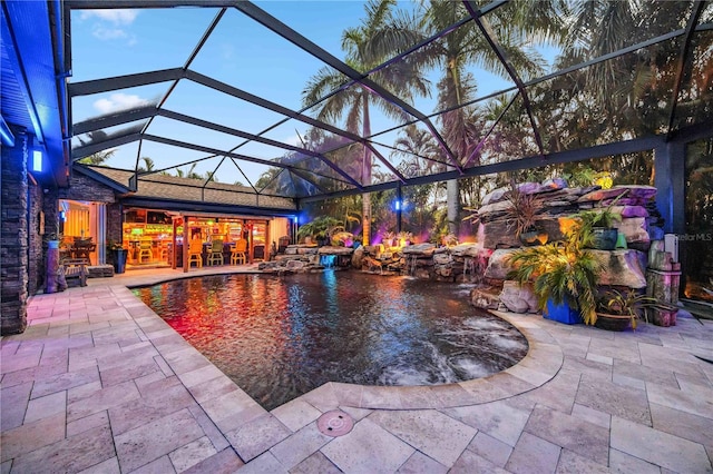 pool at dusk with a lanai and a patio area