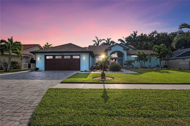 view of front of house featuring a garage, a front yard, decorative driveway, and stucco siding