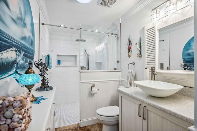 bathroom featuring crown molding, visible vents, wainscoting, vanity, and tiled shower