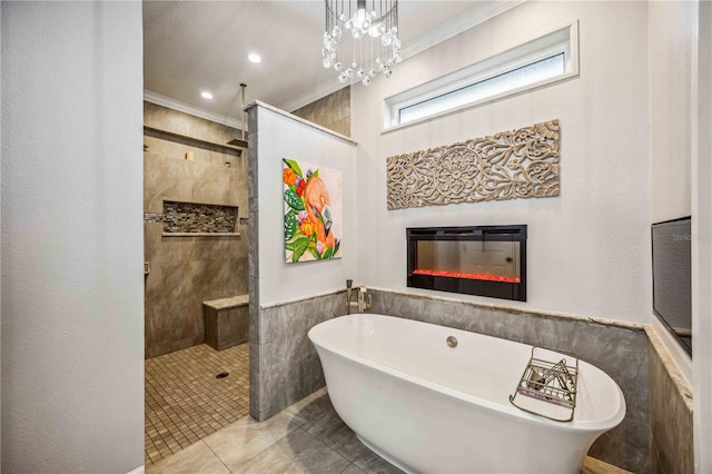 full bath with wainscoting, a glass covered fireplace, walk in shower, a freestanding bath, and crown molding