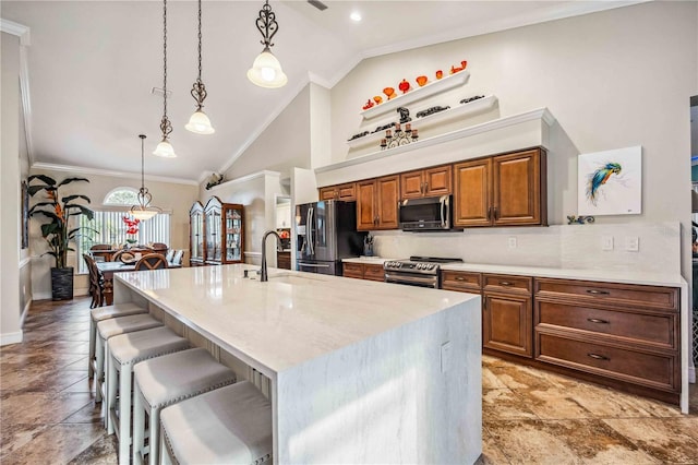 kitchen with a breakfast bar area, stainless steel appliances, a sink, brown cabinets, and crown molding