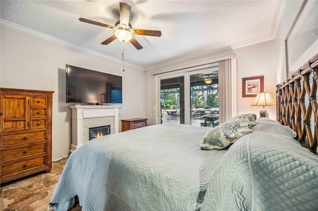 bedroom featuring a textured ceiling, access to outside, ornamental molding, and a stone fireplace