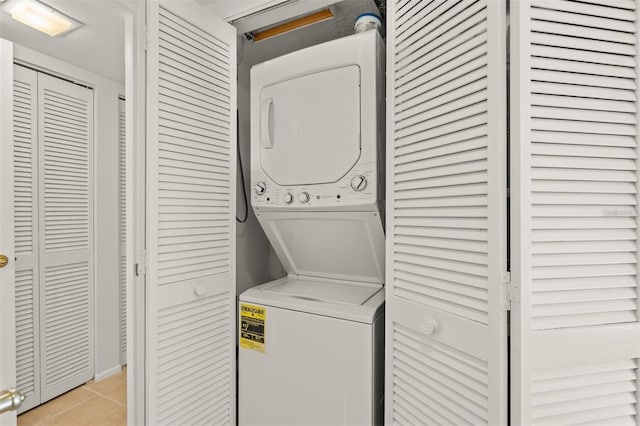 laundry room featuring stacked washer / dryer and light tile patterned floors