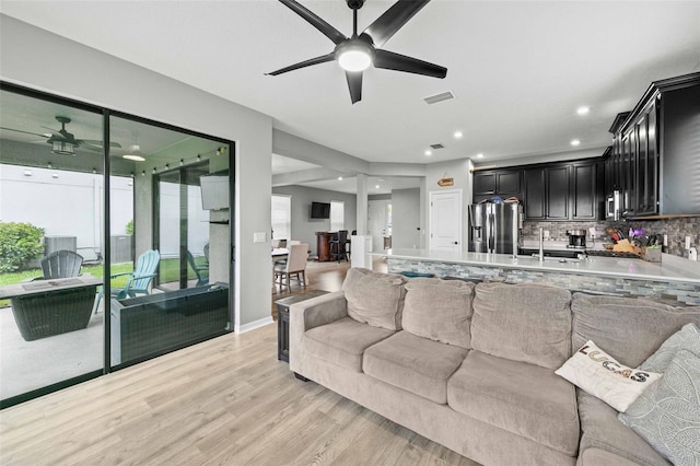 living room featuring ceiling fan, sink, and light hardwood / wood-style flooring