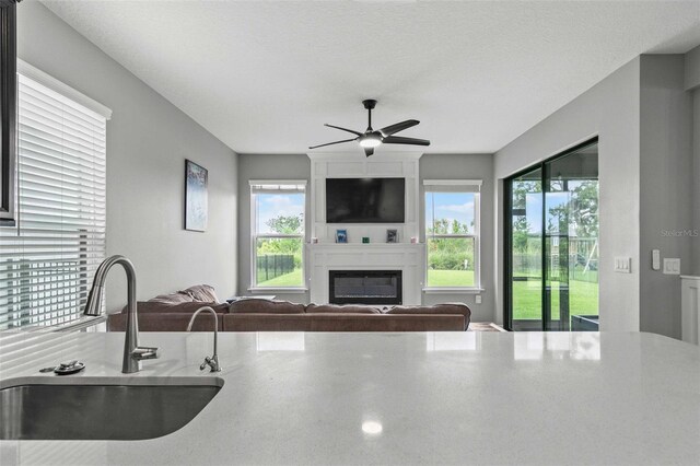 kitchen with ceiling fan, sink, a textured ceiling, and a healthy amount of sunlight