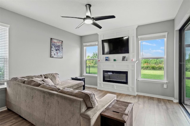 living room with light wood-type flooring, plenty of natural light, and ceiling fan