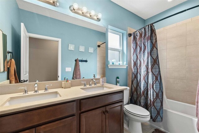 full bathroom with double vanity, toilet, shower / bath combo with shower curtain, and tile patterned floors