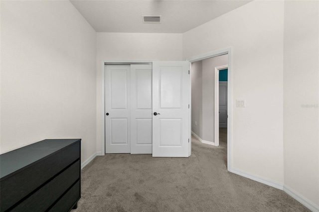 unfurnished bedroom with light carpet and a closet