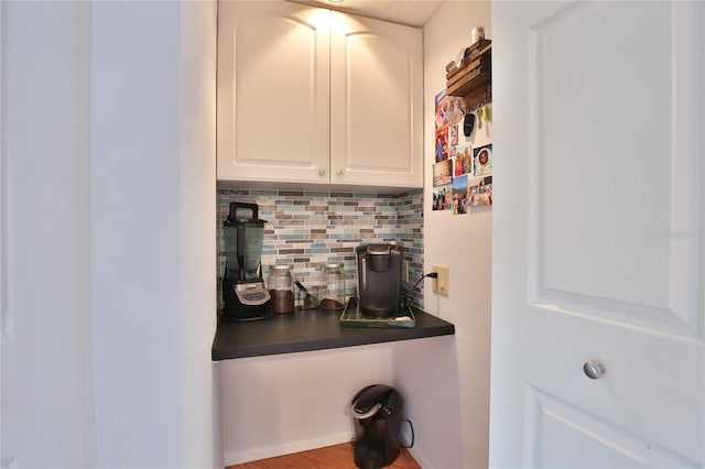 interior space with white cabinets, hardwood / wood-style flooring, and decorative backsplash