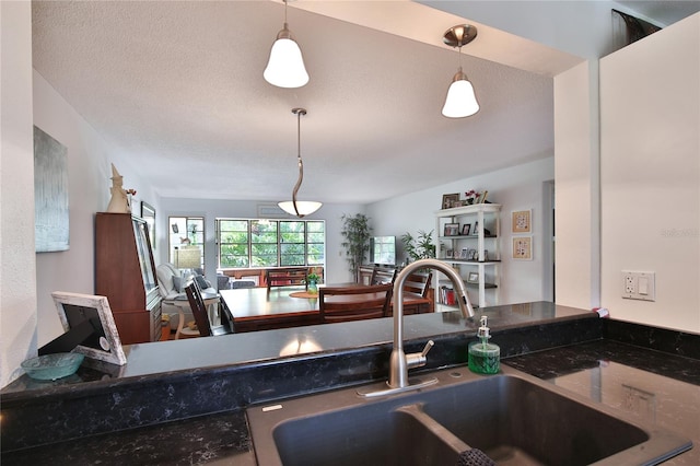 kitchen with sink, a textured ceiling, and pendant lighting