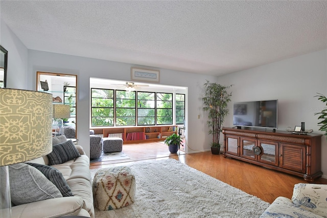 living room with ceiling fan, a textured ceiling, and hardwood / wood-style flooring