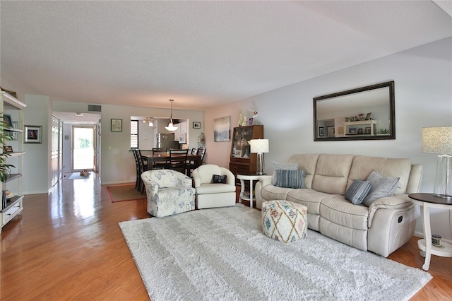 living room with light wood-type flooring and a textured ceiling