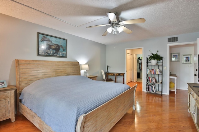 bedroom with ceiling fan, a textured ceiling, and hardwood / wood-style flooring