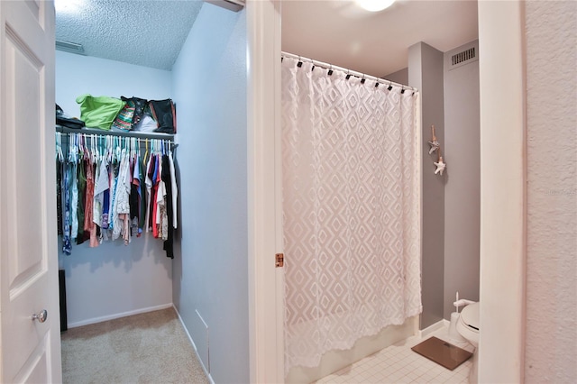 bathroom with a textured ceiling, tile patterned flooring, and toilet