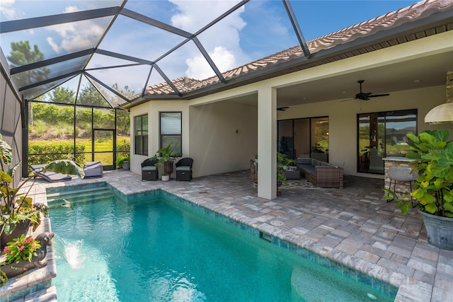 view of swimming pool featuring pool water feature, glass enclosure, a patio, and ceiling fan