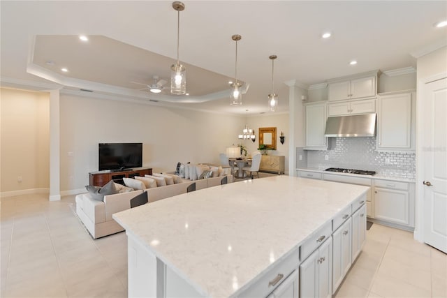 kitchen featuring white cabinets, a center island, stainless steel gas stovetop, and backsplash