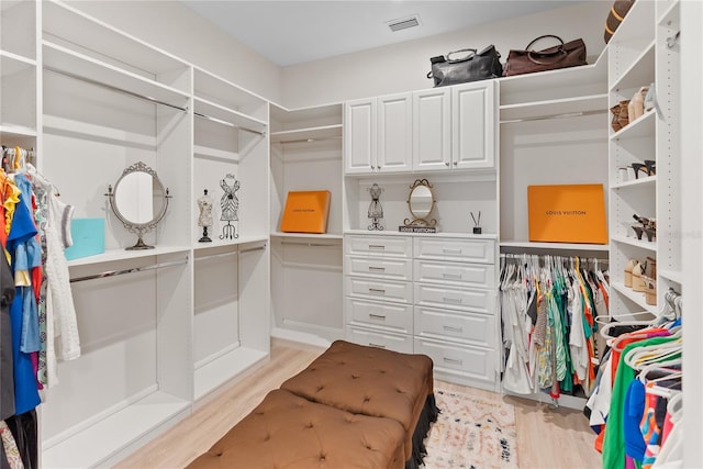 walk in closet with light hardwood / wood-style flooring