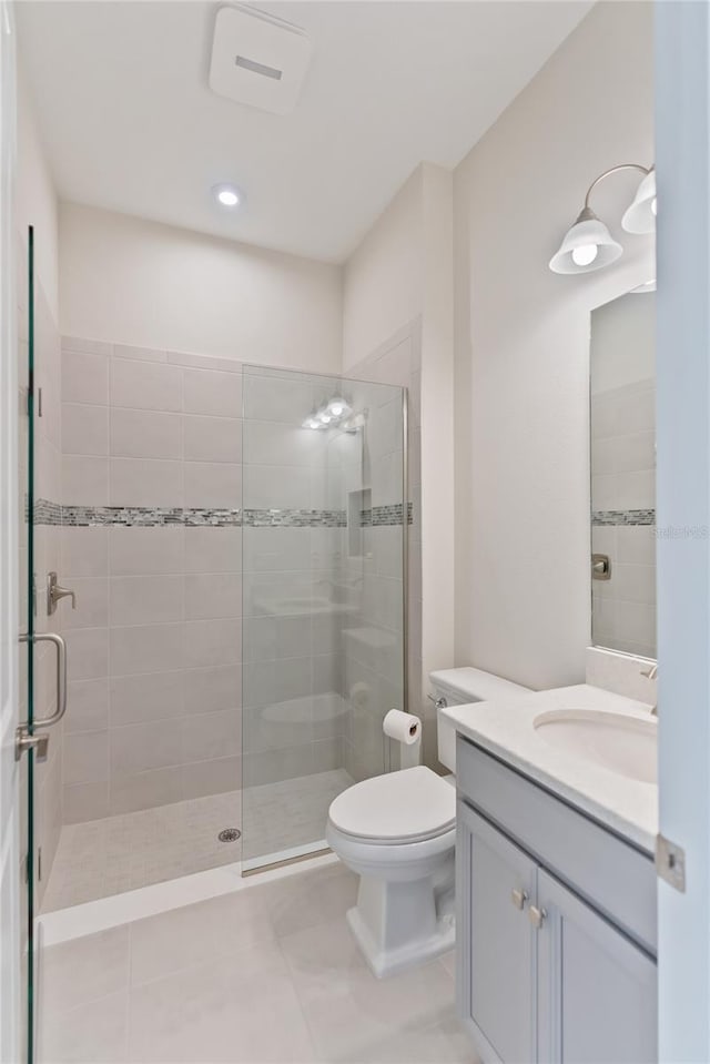 bathroom with tile patterned flooring, vanity, toilet, and a shower with door