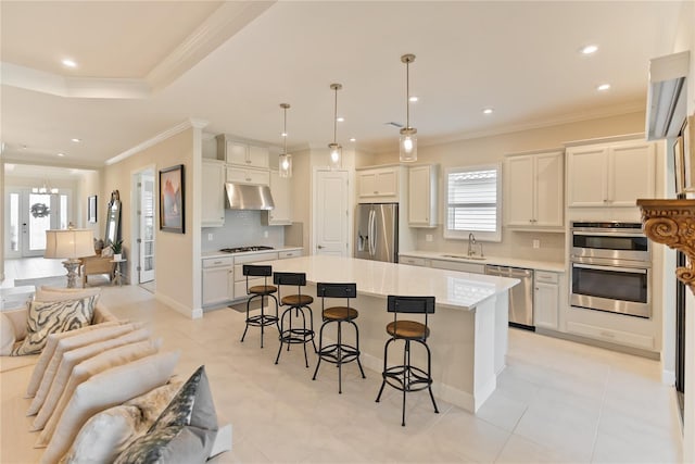 kitchen with a center island, a kitchen breakfast bar, sink, appliances with stainless steel finishes, and decorative light fixtures