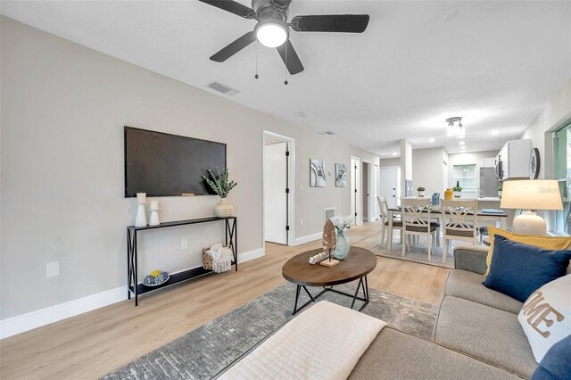 living room with light hardwood / wood-style flooring and ceiling fan