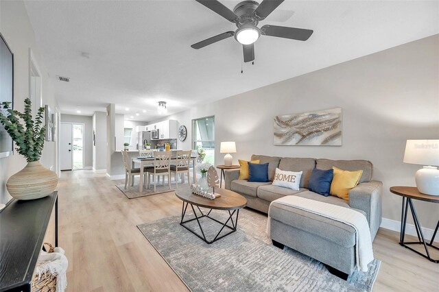 living room with ceiling fan and light hardwood / wood-style flooring