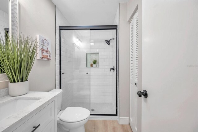 bathroom with a shower with shower door, toilet, vanity, and hardwood / wood-style flooring