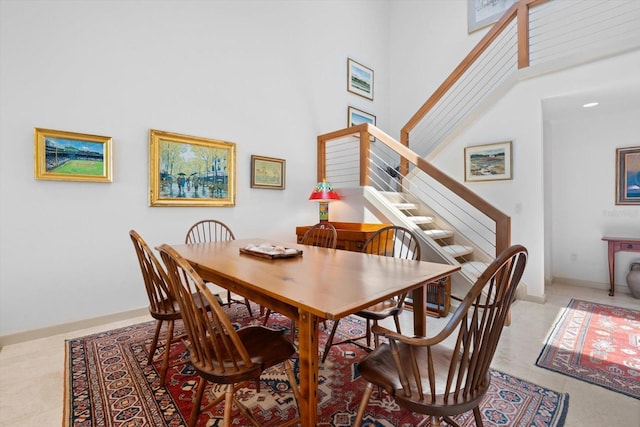 dining area featuring stairway, a towering ceiling, and baseboards