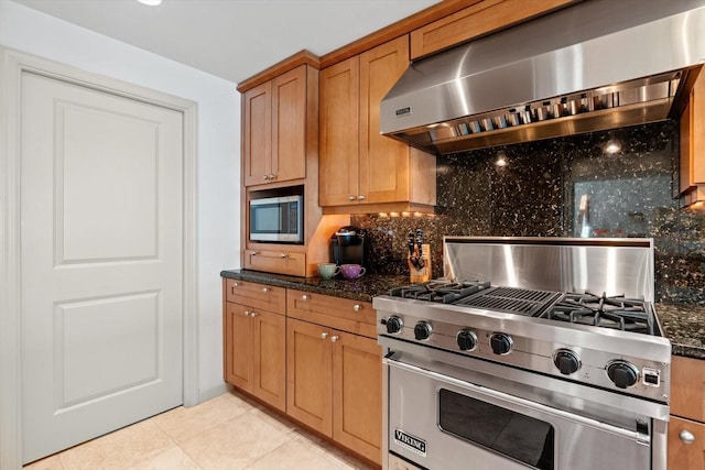 kitchen with light tile patterned floors, stainless steel appliances, range hood, decorative backsplash, and dark stone countertops