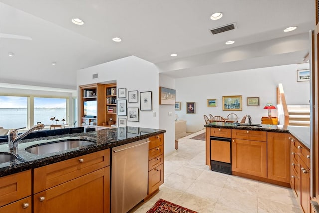 kitchen with dark stone countertops, dishwasher, and sink